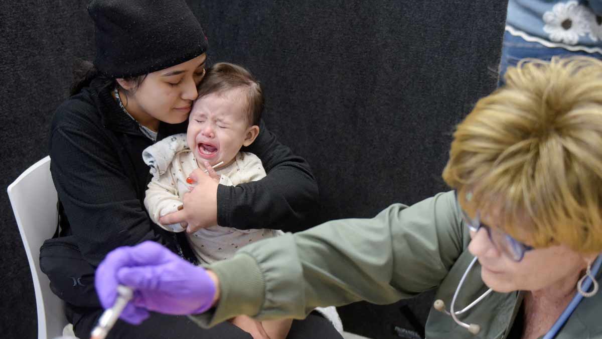 Devonay Pena comforts her 13-month-old daughter, Jaqi Herrera, after Herrera received her first dose of the MMR vaccine at the City of Lubbock Health Department in Lubbock, Texas, US | Reuters