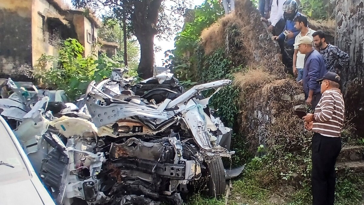 People near the wreckage of the vehicle after a car collided with a container truck at ONGC Chowk in Dehradun | PTI