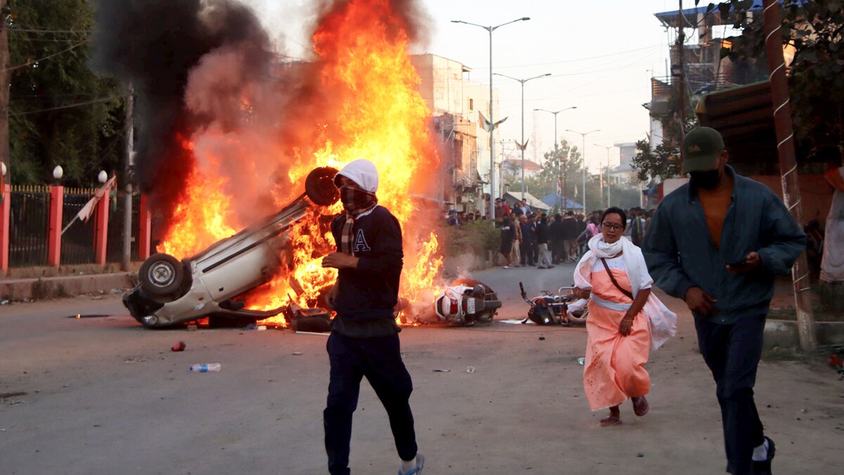 Imphal: People escape as smoke and flames billow out of vehicles which were set on fire set on fire during demonstrations after three bodies, suspected to be of six missing persons from Jiribam district, were found near the Manipur-Assam border on Friday night, in Imphal, Saturday, Nov. 16, 2024. (PTI Photo)(PTI11_16_2024_000374A)