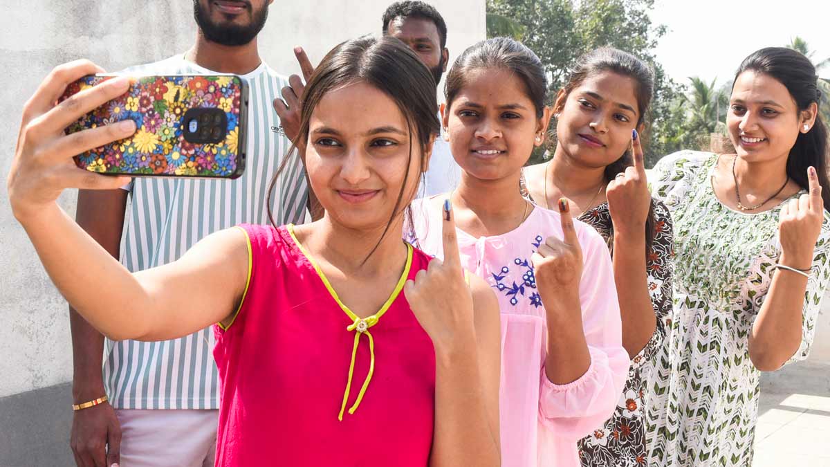 People take a selfie while showing their fingers marked with indelible ink after casting votes during the Maharashtra Assembly elections, in Solapur | PTI