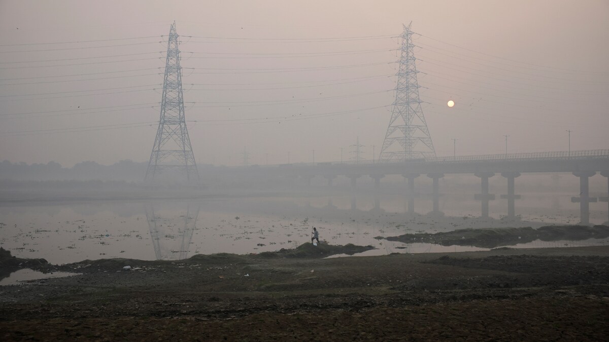 A man walks on the banks of the Yamuna river on a smoggy morning in New Delhi, India, November 4, 2024. REUTERS/Anushree Fadnavis