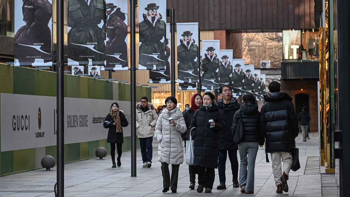 People walk at a shopping mall complex in Beijing | AFP