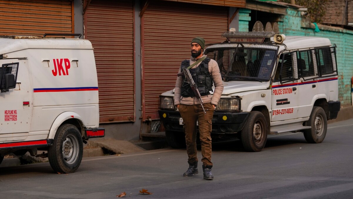 A J&K police officer stands guard on the road leading to the site of a gun battle in the outskirts of Srinagar | PTI