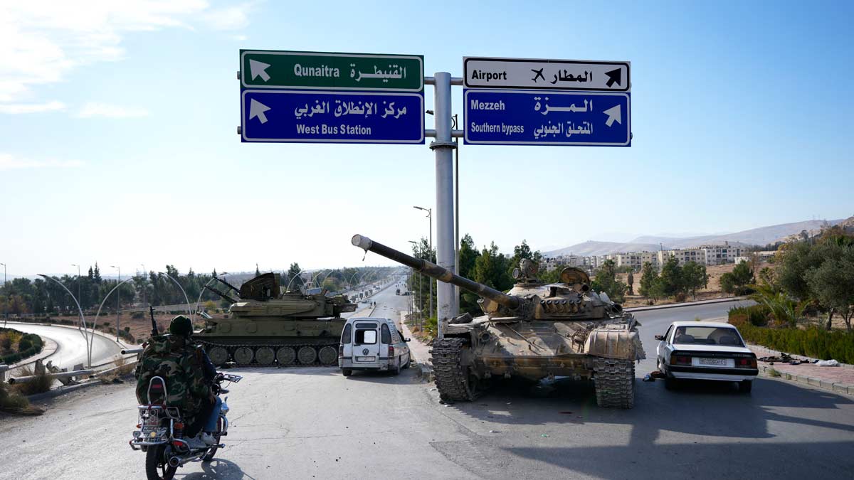 Opposition fighters drive past government forces tanks which were left on a highway in Damascus | AP