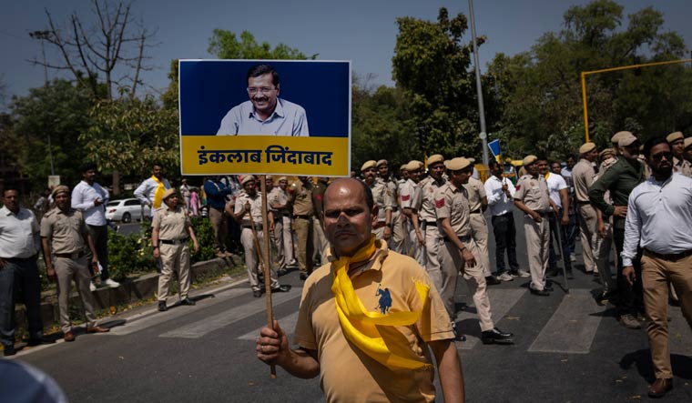 An AAP supporter holds a placard with the photograph of  Arvind Kejriwal, in New Delhi | AP