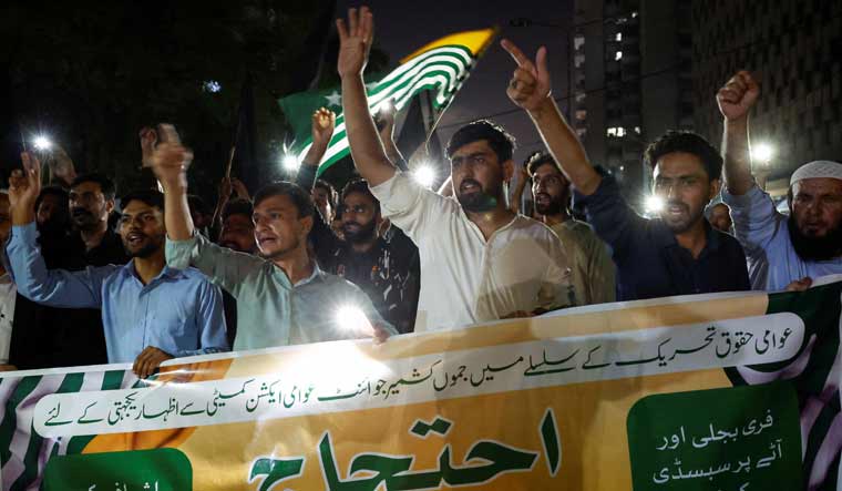 People hold a banner as they chant slogans in support of an alliance of civil rights groups protesting in Pakistan-occupied Kashmir | Reuters 