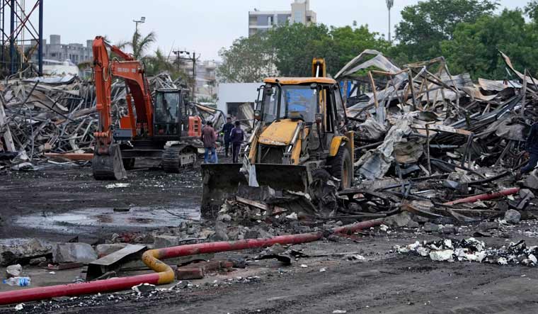 Earthmovers remove burnt debris the day after a fire broke out in an amusement park in Rajkot | AP 