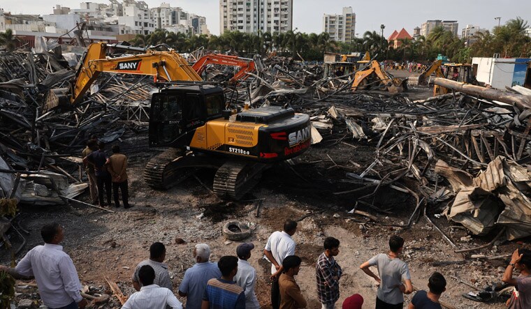 Machines move debris as onlookers watch following a fire in a gaming zone in Rajkot, in the western state of Gujarat, India, May 26, 2024. REUTERS/Amit Dave
