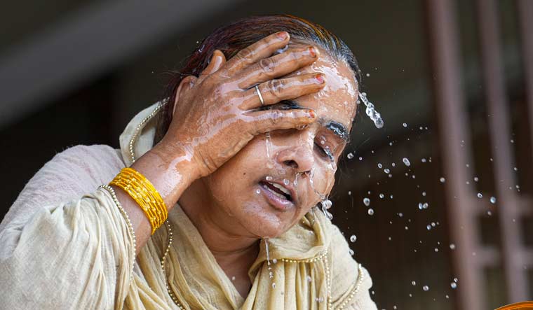A woman splashes water on her face amid heatwave in Delhi | PTI
