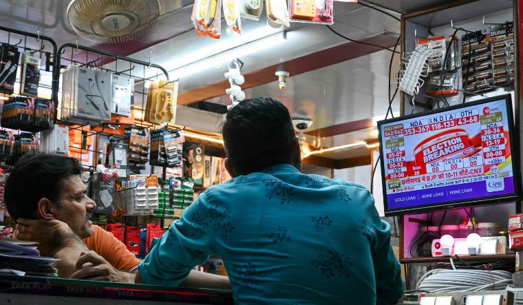 People watch exit polls released on television after voting concluded at the end of the seventh and final phase of voting in India's general election, at a store in Hyderabad on June 1 | AFP