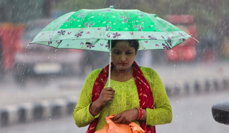 A pedestrian uses an umbrella to shield herself during rains in New Delhi | PTI