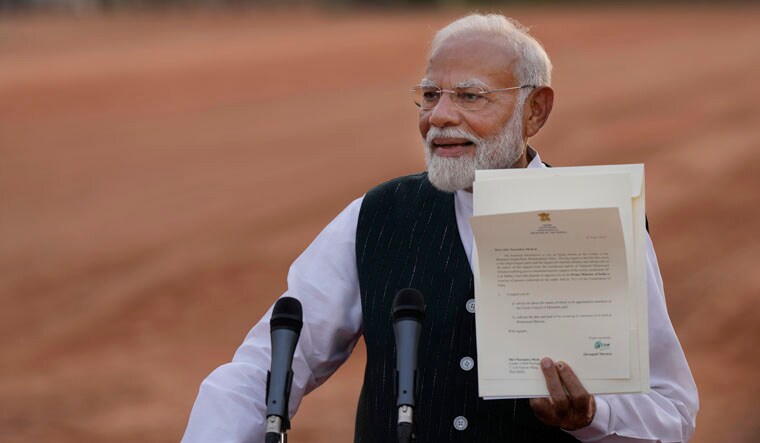 Indian Prime Minister Narendra Modi displays a letter from the President of India, Draupadi Murmu, inviting him to form the next central government, outside the Rashtrapati Bhavan in New Delhi, India, Friday, June 7, 2024. (AP Photo/Manish Swarup)