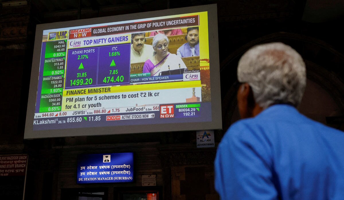 A man watches a screen displaying India's Finance Minister Nirmala Sitharaman's budget speech at a railway station in Mumbai | Reuters