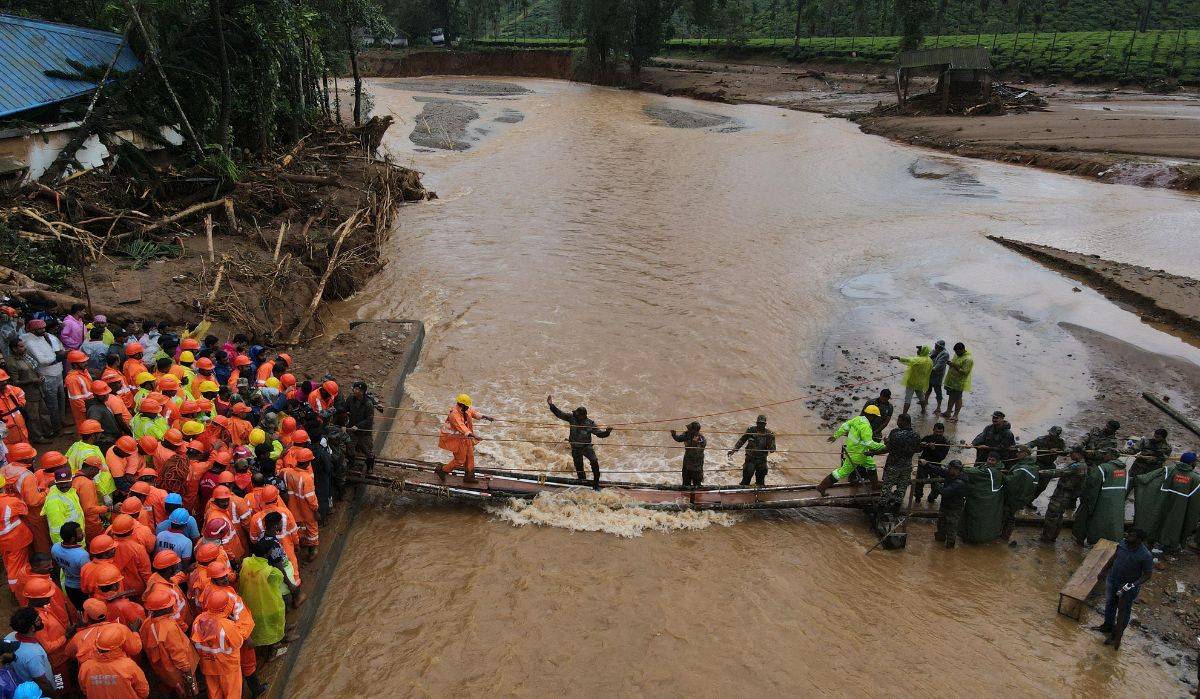 A drone view shows members of rescue teams crossing a temporary bridge to reach to a landslide site after multiple landslides in the hills in Wayanad district on July 31, 2024 | Reuters