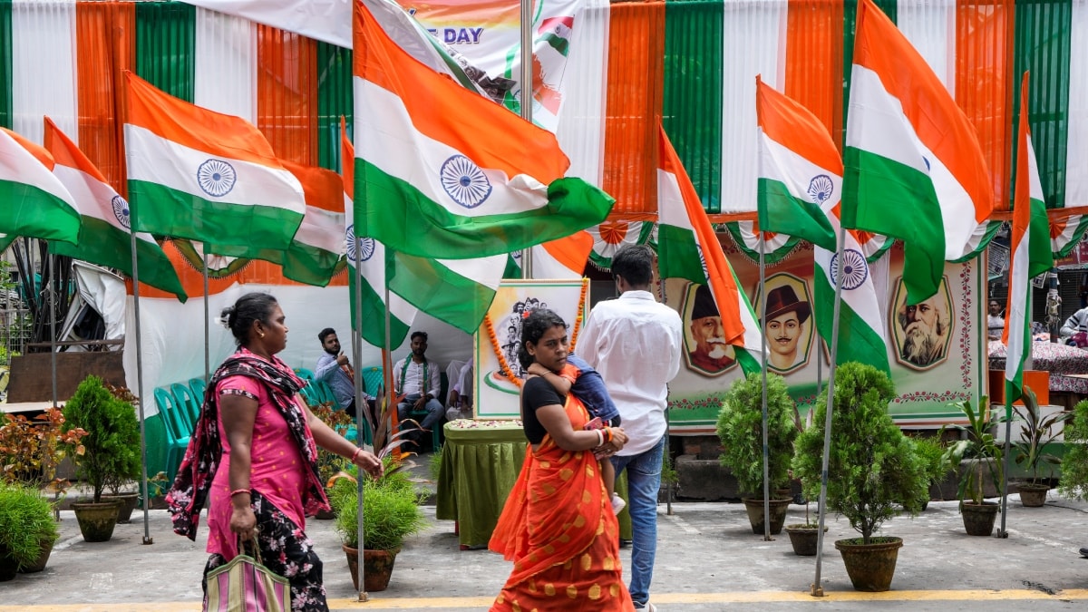 Commuters walk on a street decorated with Indian national flags during the country's Independence Day celebrations | AP