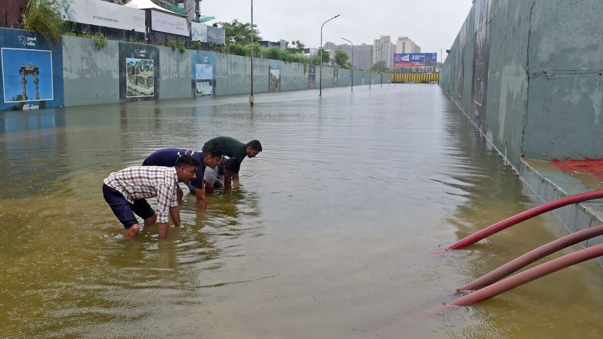 Rescue workers from the Gandhinagar Fire and Emergency Services effort to remove water from a flooded underpass after heavy rains on the outskirts of Ahmedabad | AFP
