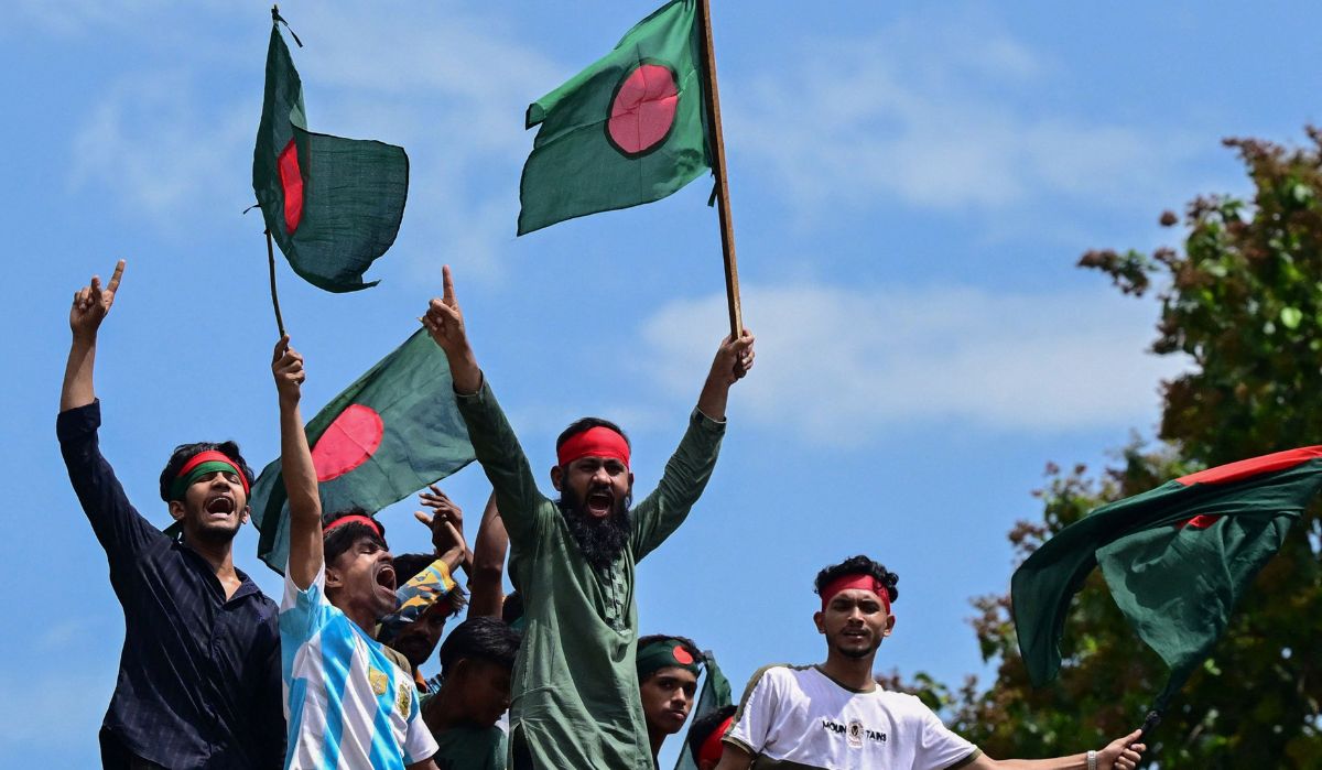 Protesters wave national flags as they stand over the Anti Terrorism Raju Memorial Sculpture during a protest in Dhaka on August 4, 2024 | AFP