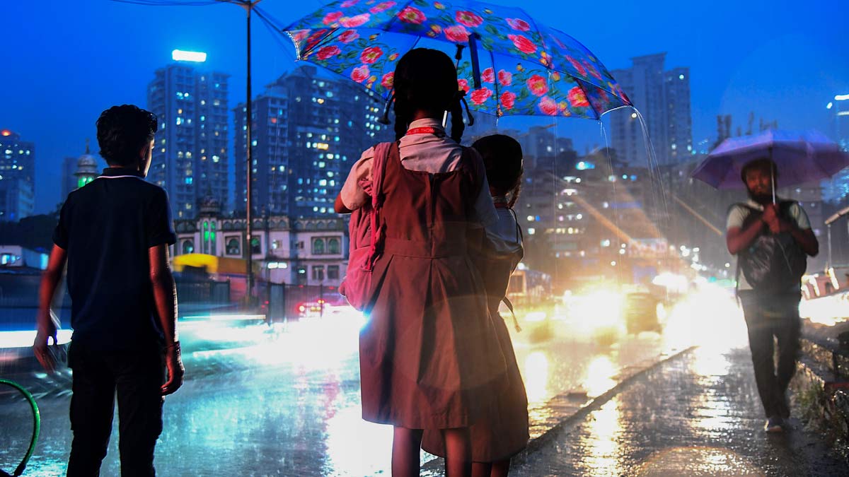 Two school students share an umbrella to shield themselves during rain, in Mumbai | PTI