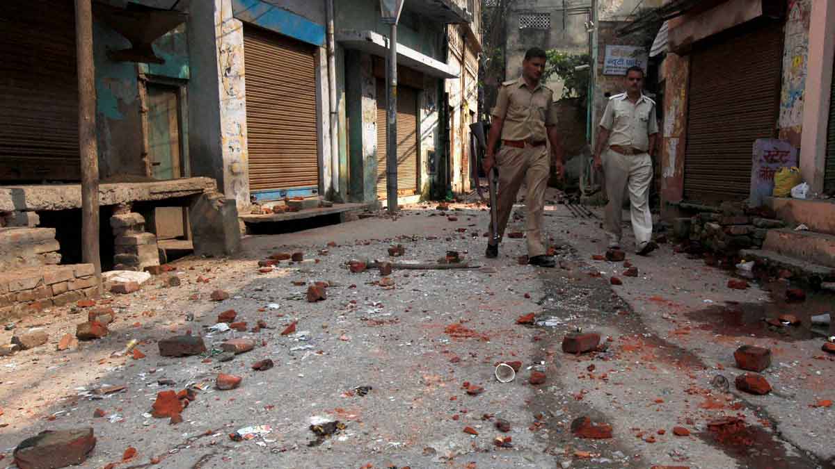 (File) Policemen walk on a road littered with bricks and stones thrown during the communal clash in Muzaffarnagar in Uttar Pradesh | PTI