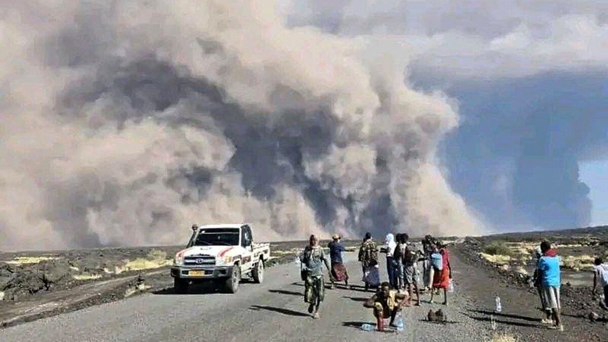 In this photo released by the Afar Government Communication Bureau, people watch ash billow from the first time eruption of the Hayli Gubbi Volcano in Ethiopia's Afar region Sunday, Nov. 23, 2025. (Afar Government Communication Bureau via AP)