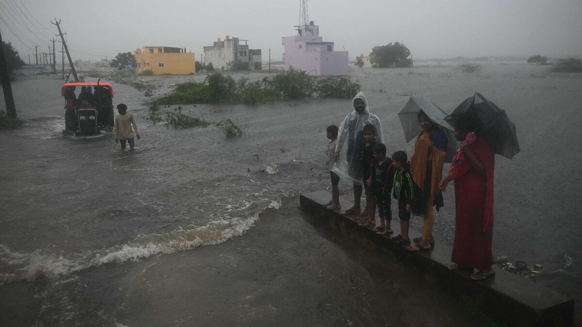 Rescue personnel use a tractor to evacuate stranded people from the flood affected area, amid heavy rain due to cyclone Ditwah, on the outskirts of Chennai, on December 3, 2025. (Photo by R.Satish BABU / AFP)