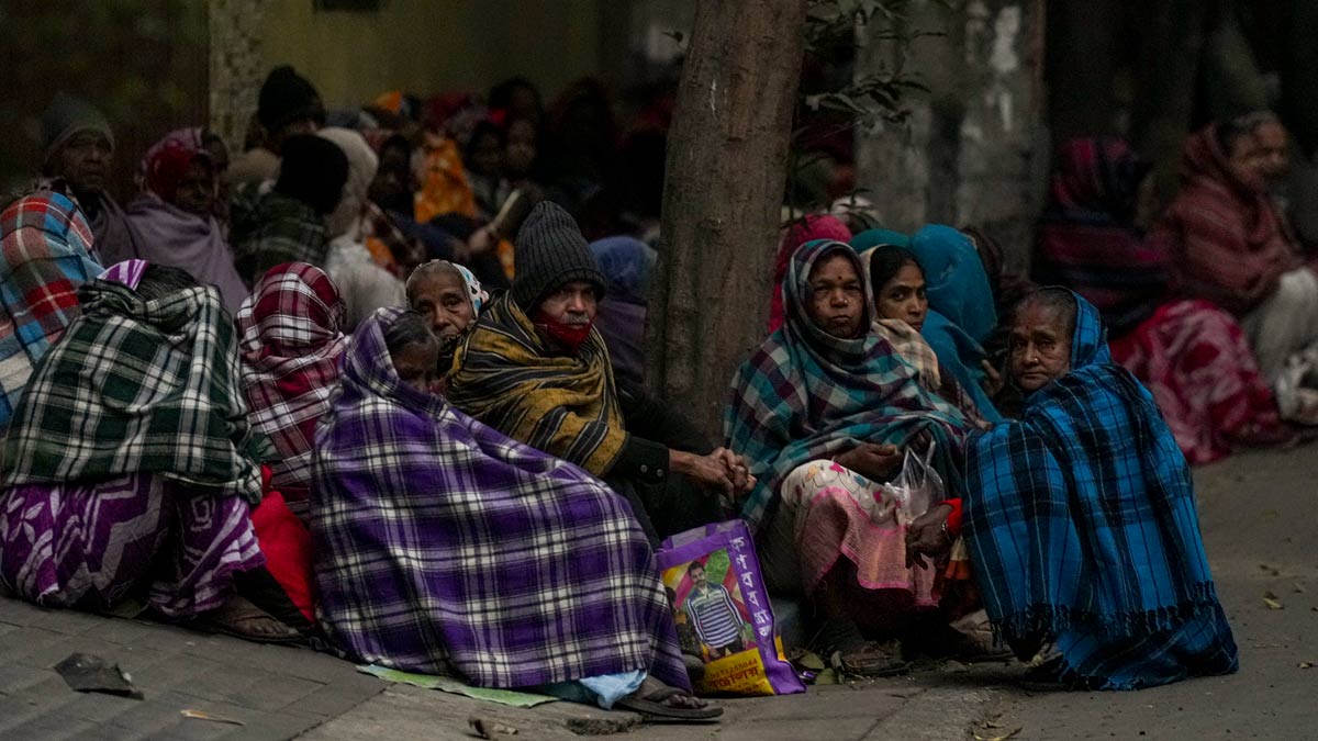 Workers sit on a pavement wearing woollen clothes on a cold winter morning, in Kolkata | PTI