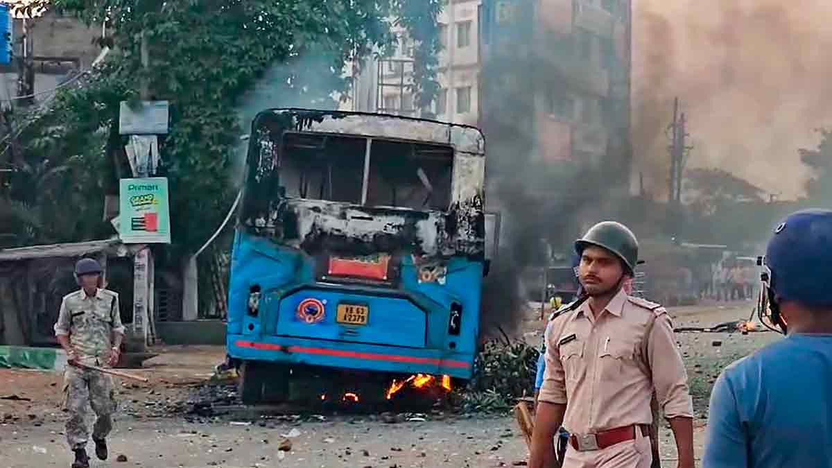 Security personnel stand near a torched vehicle during a protest against Waqf (Amendment) Act, in Murshidabad | PTI