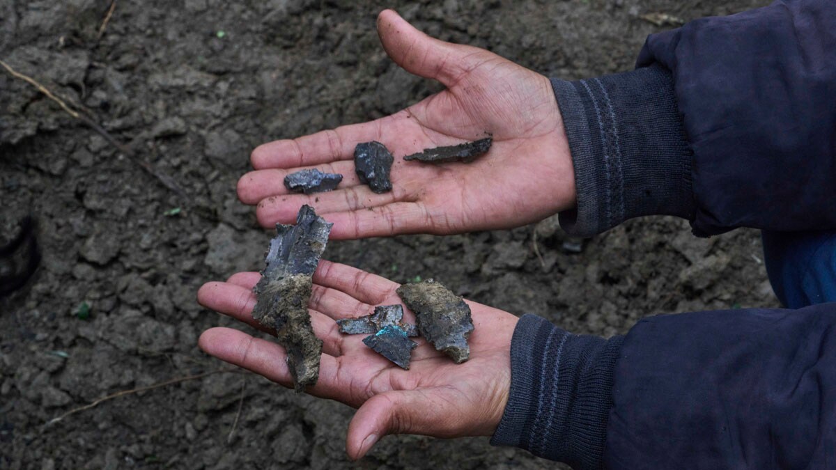 Kashmiri villager Mohammad Rafiq displays shrapnel of a shell as he sits near a crater outside his damaged house following overnight shelling from Pakistan at Gingal village in Uri district, Indian controlled Kashmir, Friday, May 9, 2025. (AP Photo/Dar Yasin)