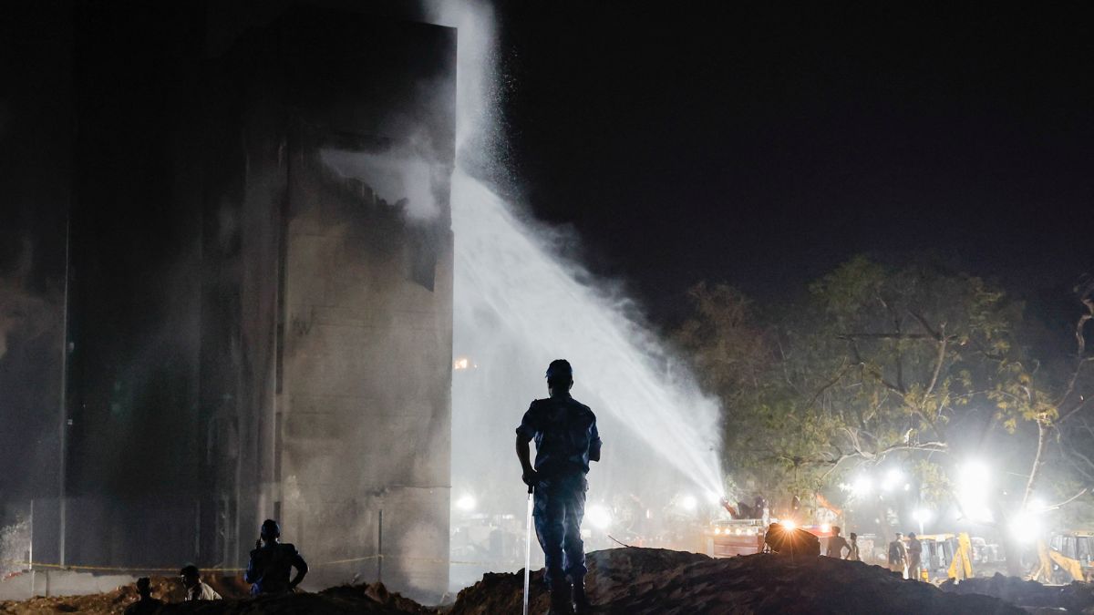 A jet of water is sprayed onto a building as security personnel stand at the crash site after an Air India aircraft crashed during take-off from an airport in Ahmedabad | Reuters