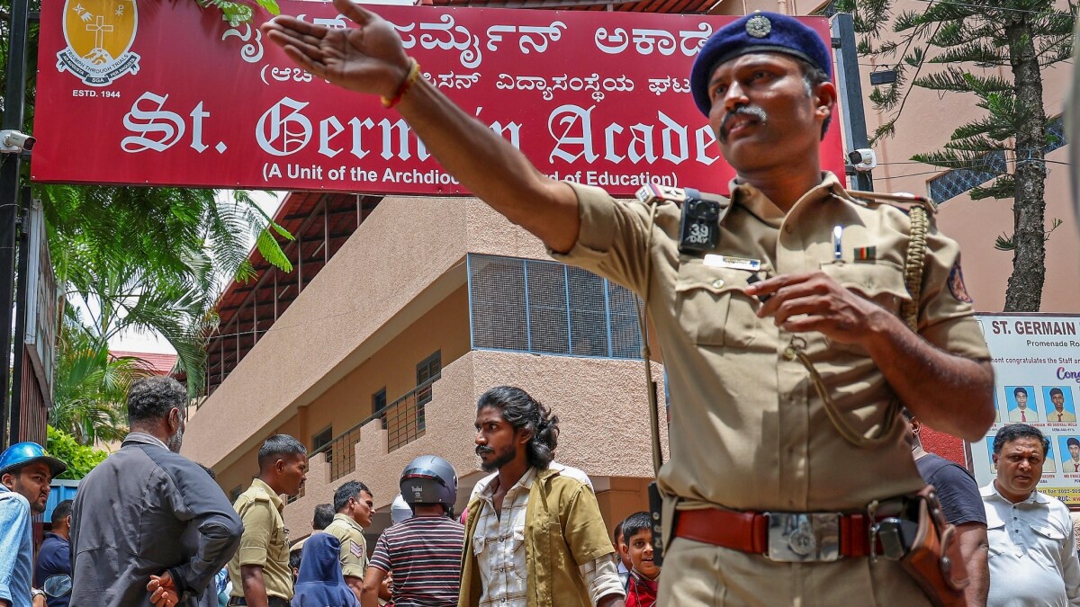 A police official stands guard as parents arrive to take their children home after a bomb threat at St. Germain Academy in Bengaluru | PTI