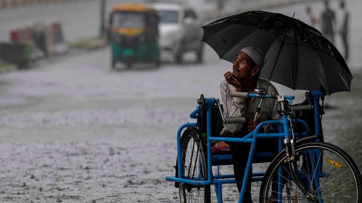 [FILE] A physically challenged man looks towards the sky as he travels through a waterlogged road amid monsoon rain | PTI