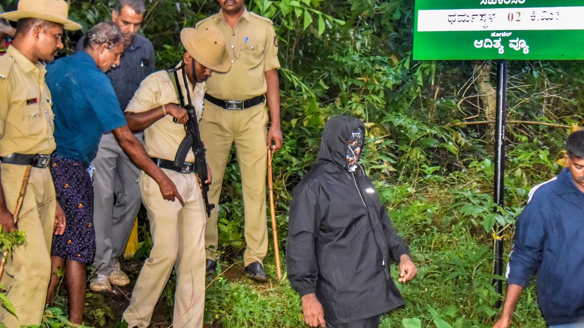 (File image) Security personnel with the whistleblower, in mask, near a site of an alleged burial related to the Dharmasthala mass burial case | PTI 