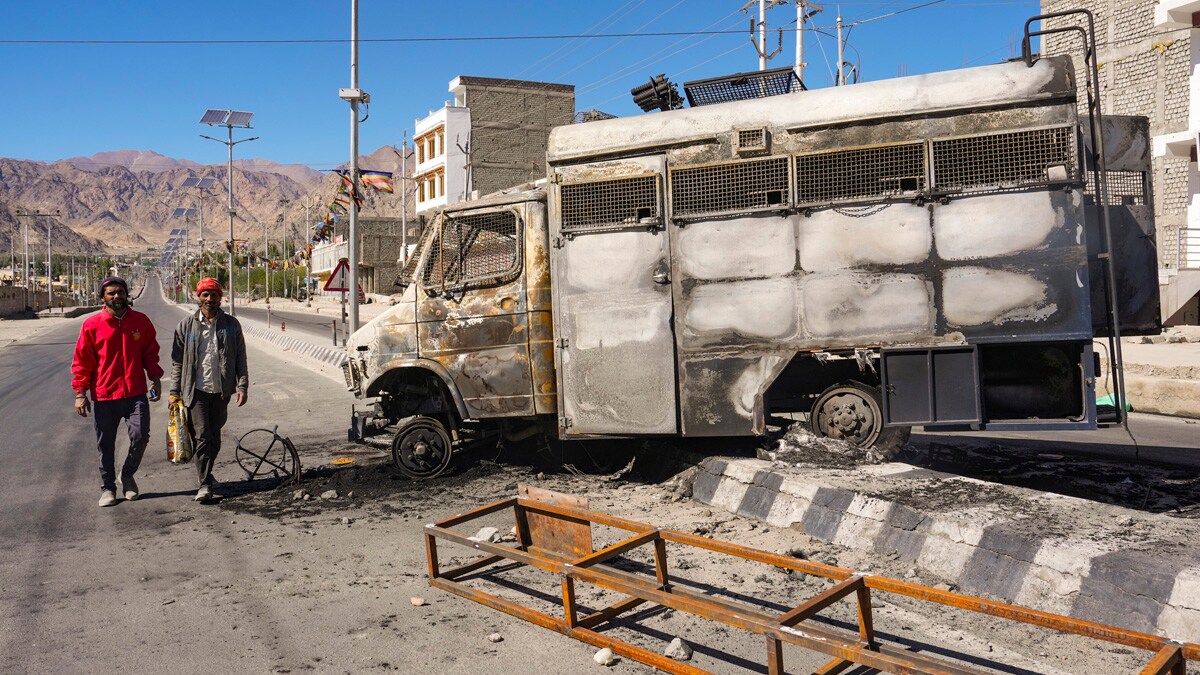 Leh: People pass by a charred vehicle, in the aftermath of violent clashes between demonstrators and police during a protest demanding statehood for Ladakh, in Leh, Thursday, Sept. 25, 2025. (PTI Photo)(PTI09_25_2025_000305A)
