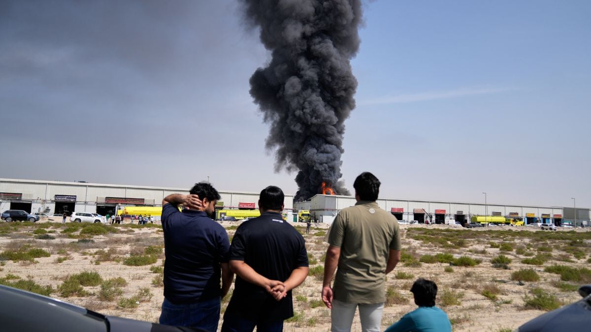 Residents watch as the flames and a black plume of smoke rises from a warehouse at the industrial area of Sharjah City in the United Arab Emirates following reports of Iranian strikes in Dubai, United Arab Emirates | AP