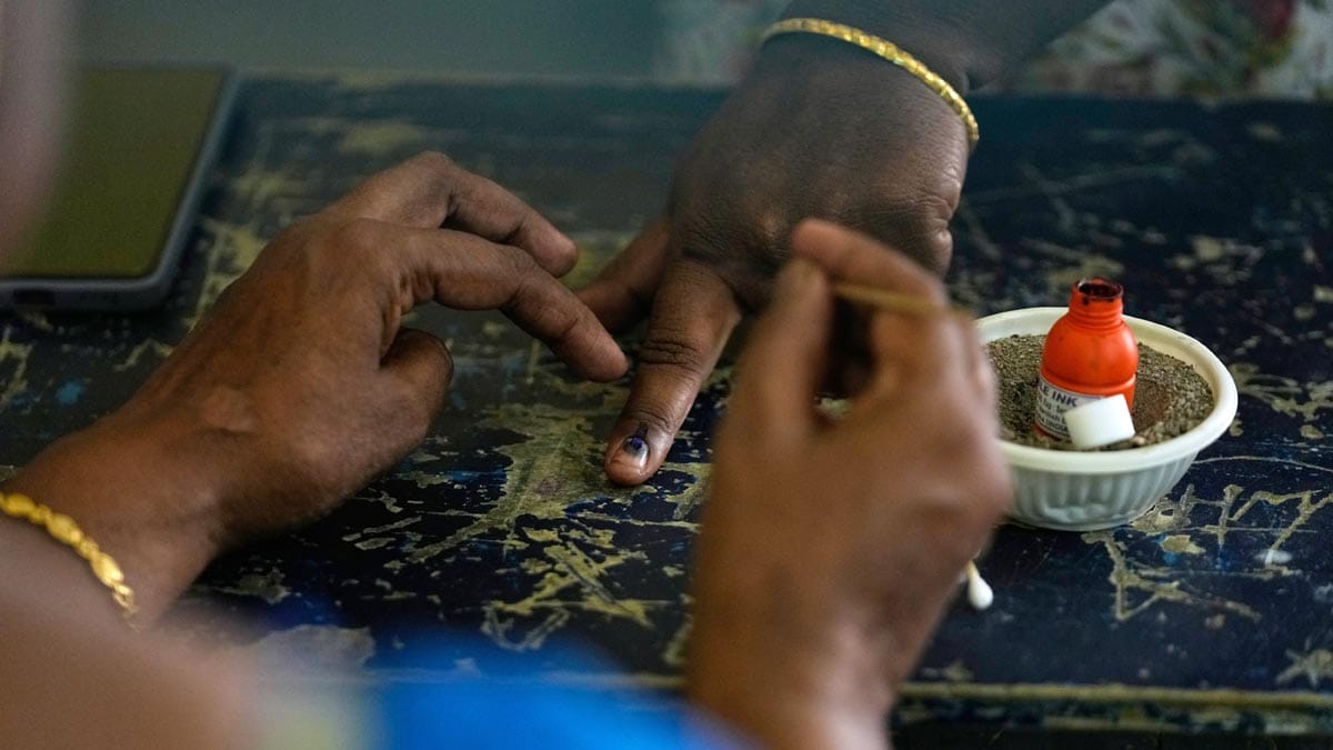 A polling officer marks the finger of a woman with indelible ink inside a polling station during the Tamil Nadu state assembly elections in Chennai | AP