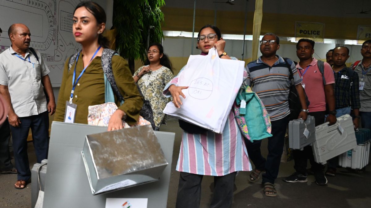 Election officials carry electronic voting machines (EVM) and other polling materials on the eve of the second phase of the West Bengal assembly elections at Netaji Indoor Stadium in Kolkata | Salil Bera