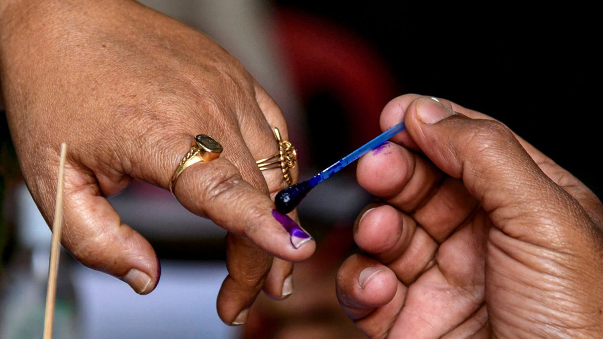 A polling official marks the finger of a voter with indelible ink before casting a vote in the Assam Assembly elections | PTI