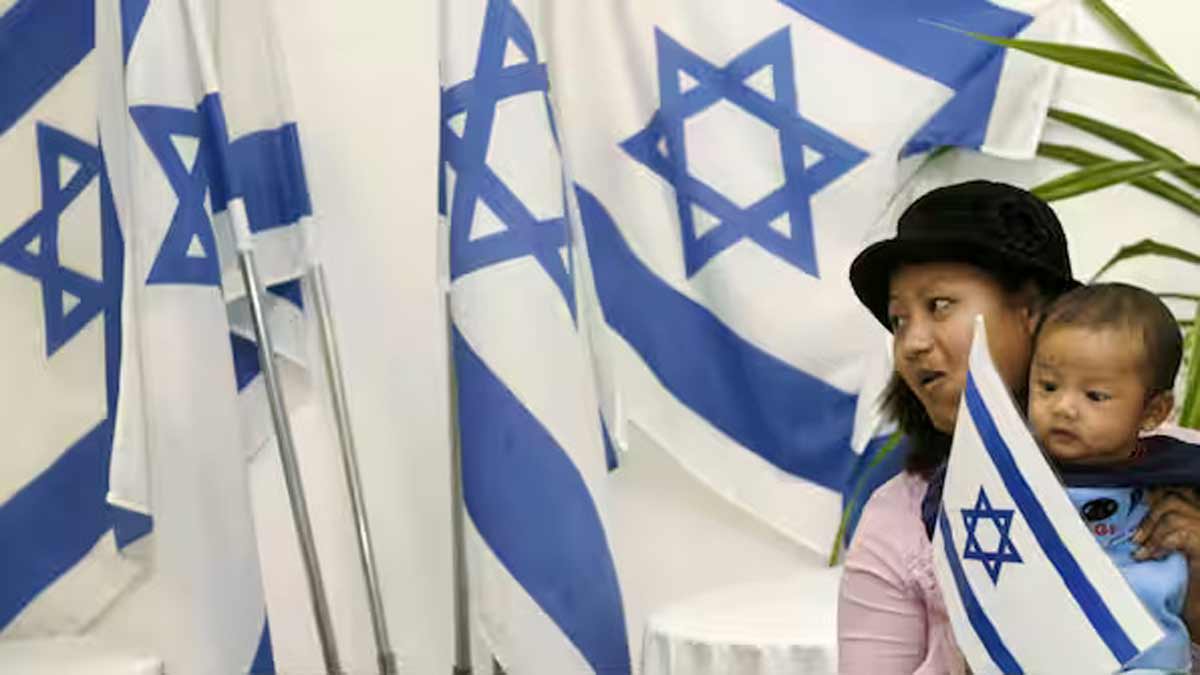 A newly arrived Jewish immigrant from India holds a child beside Israeli flags after arriving at Ben Gurion international airport near Tel Aviv | Reuters
