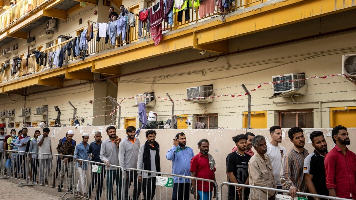 Workers wait at a distribution point to receive a charity "iftar" meal at a complex housing foreign labourers in Dubai | AFP