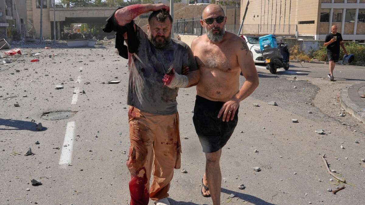 An injured man is helped to leave after a missile hit from Iran in Israel's Haifa | AP