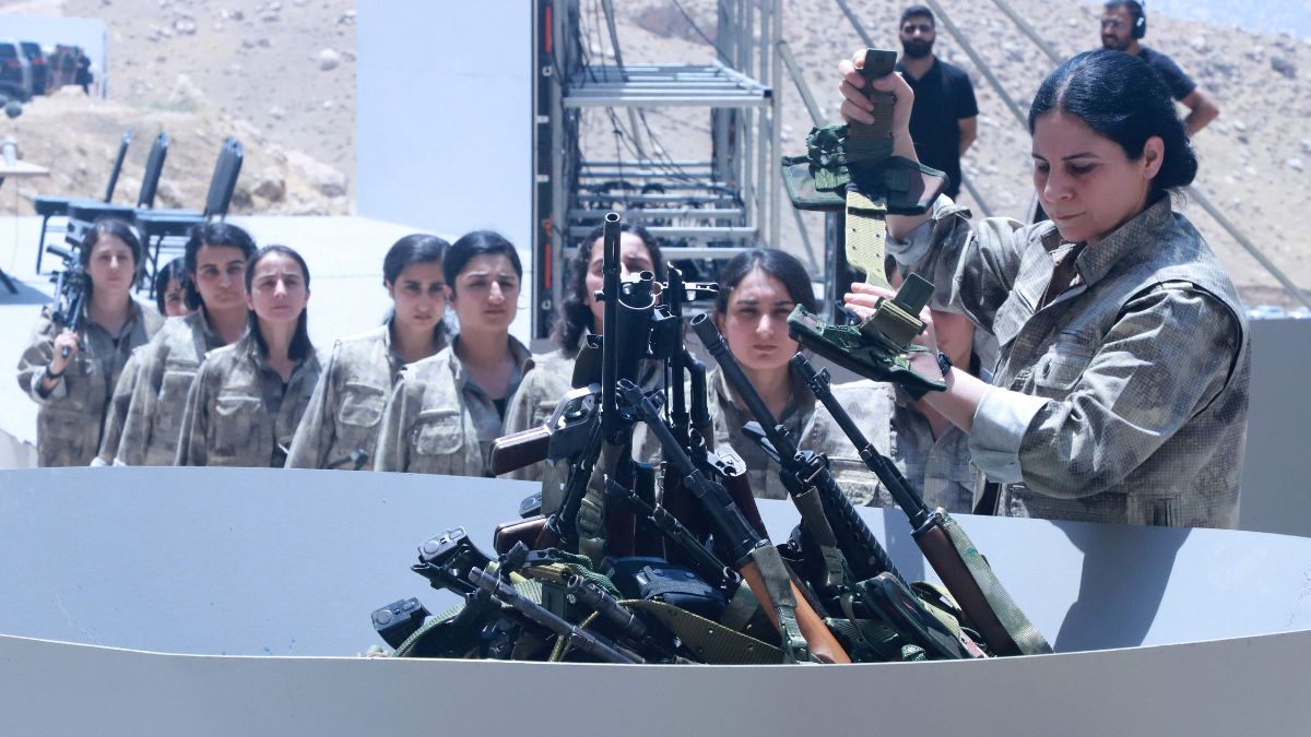 Fighters with the Kurdistan Workers' Party (PKK) line up to put their weapons into a pit during a ceremony in Sulaimaniyah, in Iraq's autonomous Kurdistan region | AFP