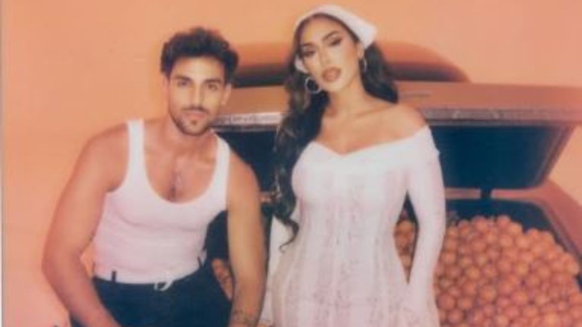 Image from Huda Beauty's 'Kalamantina' lip oil campaign showing Huda Kattan and Saint Levant posing in front of a car with  clementine oranges | X 