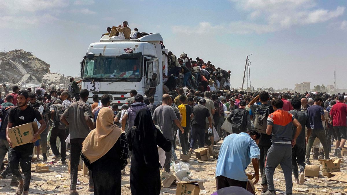 Displaced Palestinians carry food parcels as they raid trucks carrying humanitarian aid in Khan Yunis, in the southern Gaza Strip | AFP