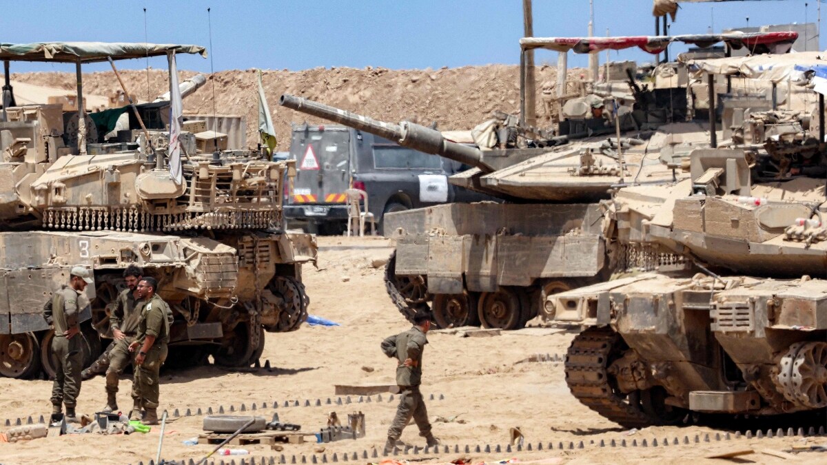 Israeli army soldiers perform maintenance tasks near main battle tanks positioned near the border with the Gaza Strip in southern Israel | AFP