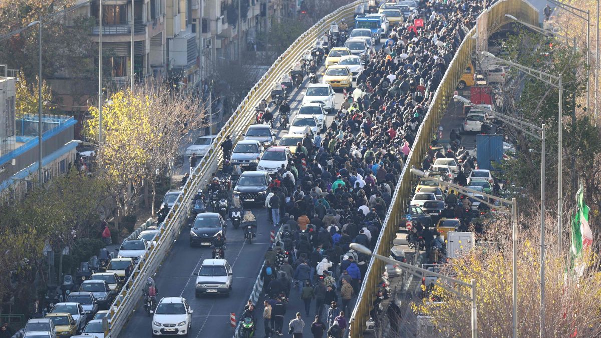 Shopkeepers and traders walk over a bridge during a protest against the economic conditions and Iran's embattled currency in Tehran | AFP 