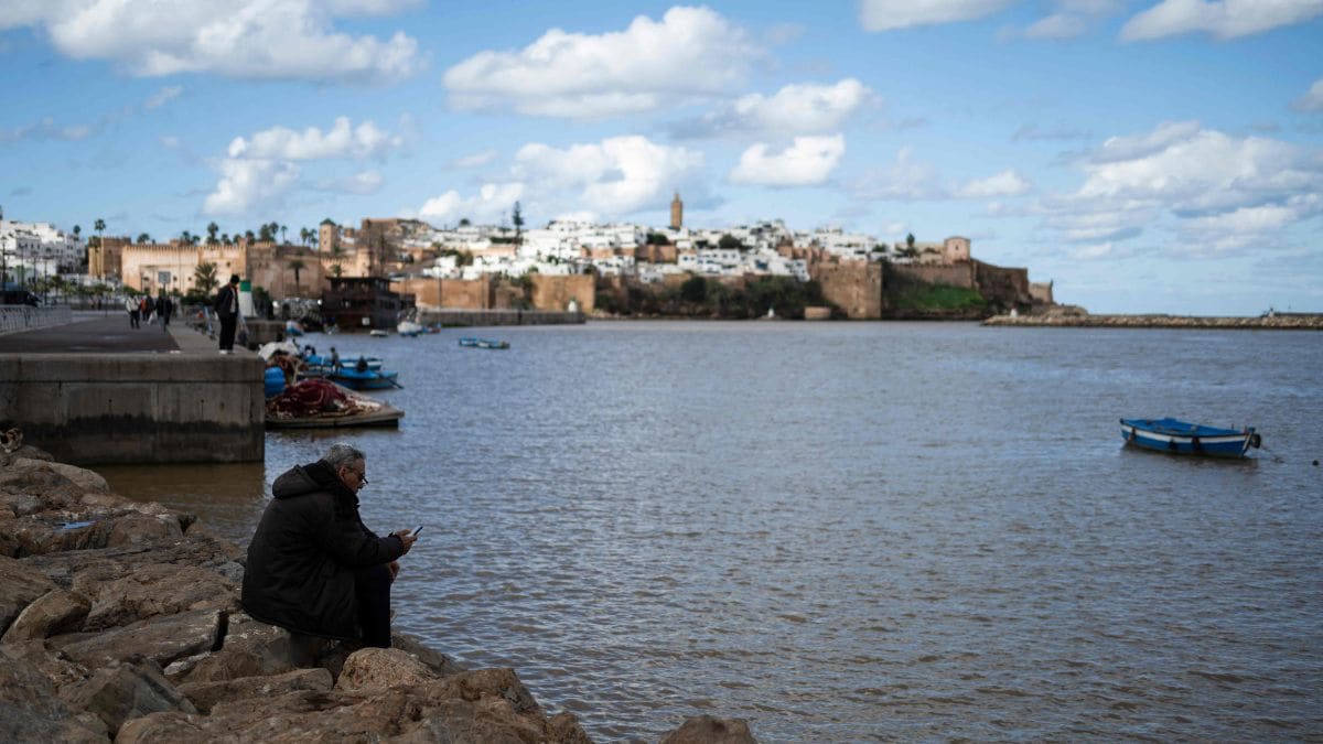 A man uses his moible phone while sitting on the bank of the Bou Regreg River in Rabat | AFP