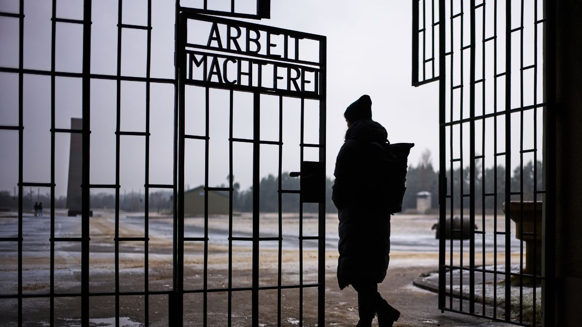 A women enters the Nazi Concentration Camp Sachsenhausen through gate with the phrase: "Arbeit macht frei", Work makes free, on the eve on the International Holocaust Memorial Day in Oranienburg, Germany | AP 