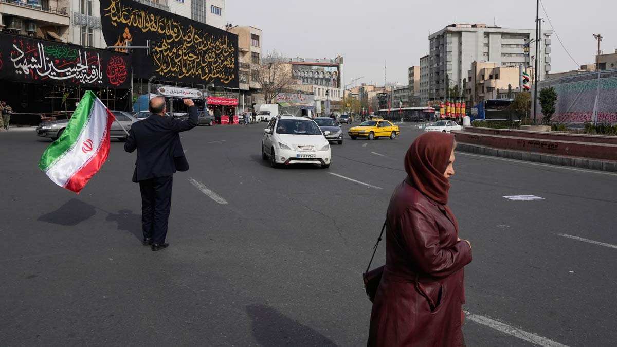 A man waves an Iranian flag during a campaign in support of the government at the Enqelab-e-Eslami, or Islamic Revolution square in downtown Tehran, Iran | AP