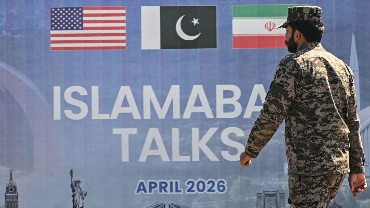 A Pakistani Ranger walks past a billboard for the US-Iran peace talks in Islamabad | X