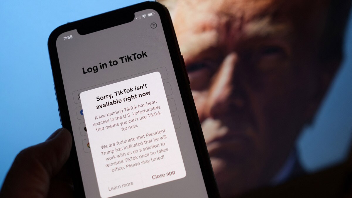 This illustration photo taken in Los Angeles on January 18, 2025, shows the TikTok app on a smartphone screen in front of a photo of US President-elect Donald Trump. TikTok disconnected access to its users in the United States late January 18 after no action was taken shortly before a national ban was to take effect, in the name of national security, unless its Chinese owners reach a deal to sell it to non-Chinese buyers by January 19, with President-elect Donald Trump unable to intervene until he takes office. "A law banning TikTok has been enacted in the US," said a message to users attempting to use the app. "Unfortunately, that means you can't use TikTok for now." (Photo by Chris DELMAS / AFP)